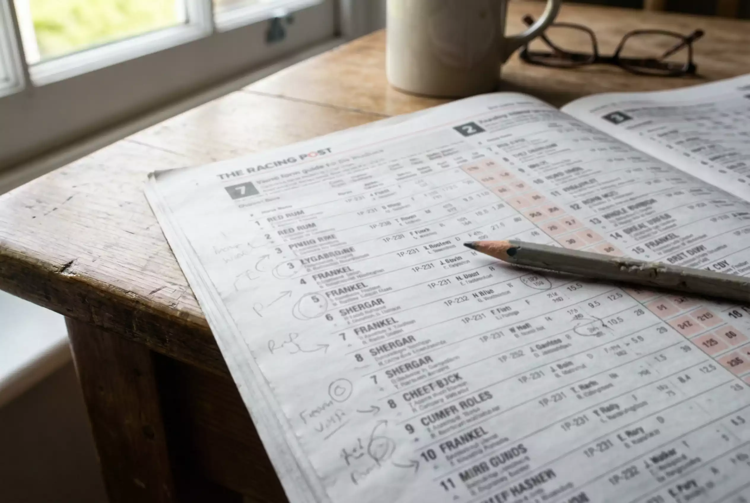 Racing newspaper form guide pages spread out with pencil markings and highlights